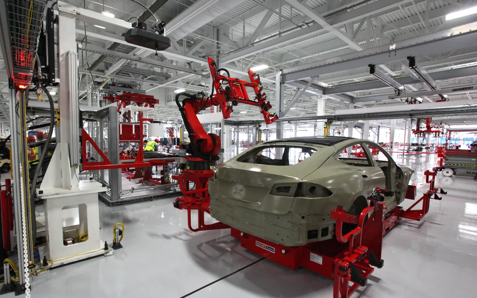 A robotic manufacturing arm in a Tesla factory installing equipment on a vehicle during production